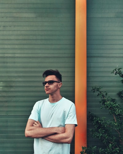 站在橙色立柱旁边的男士白色圆领T恤